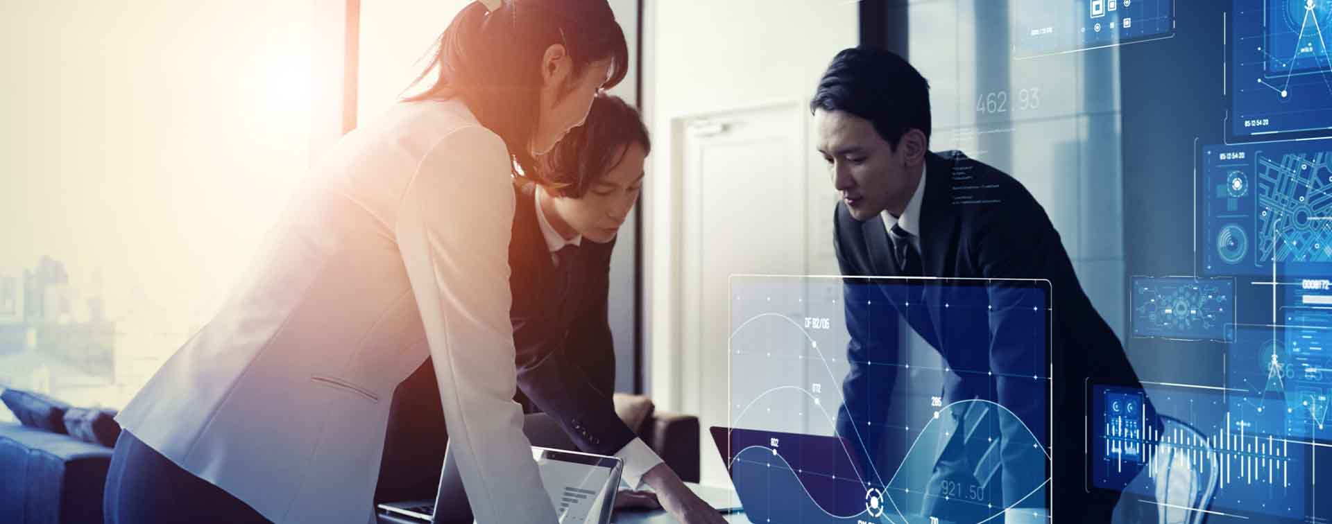 Three businesspeople in discussion around two laptops