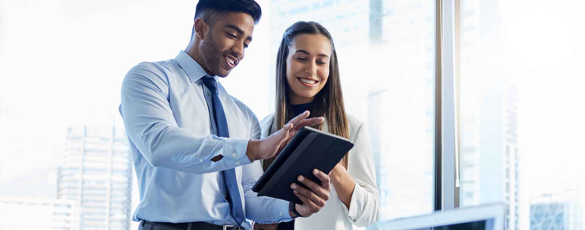 Two smiling businesspeople looking at something on a tablet
