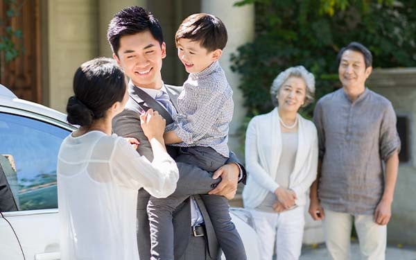 Mother and smiling father holding their child while a smiling older couple watches them in the background