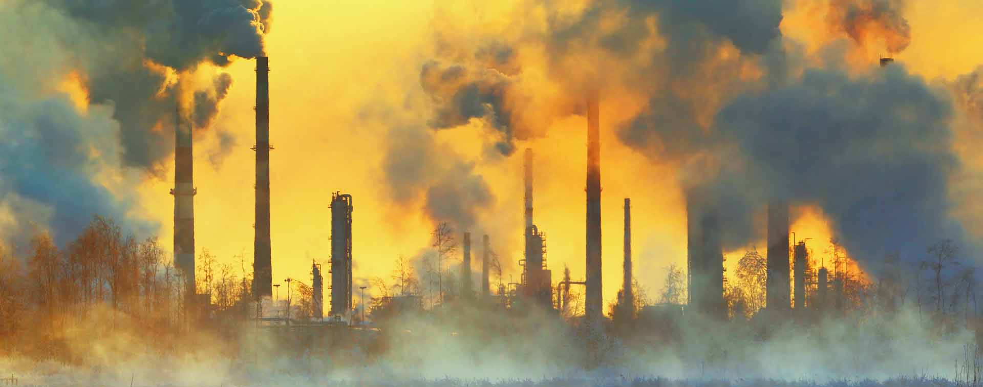 Orange sky being filled by smoke from various smokestacks.