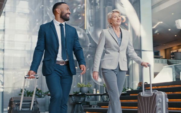 Business man and woman walking with suitcases through an airport